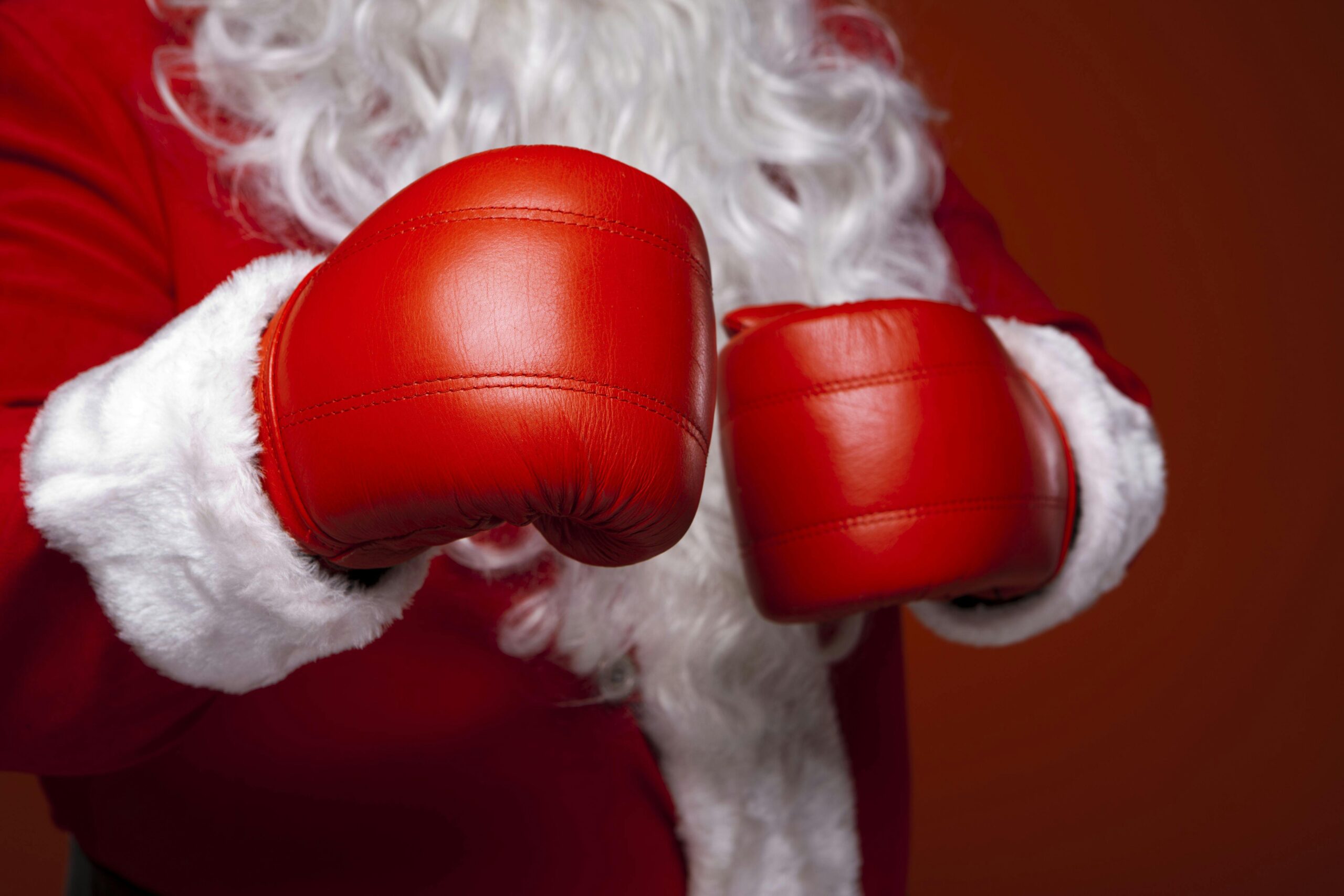 Santa Claus wearing red boxing gloves, ready for the holiday season. Close-up of costume and gloves.