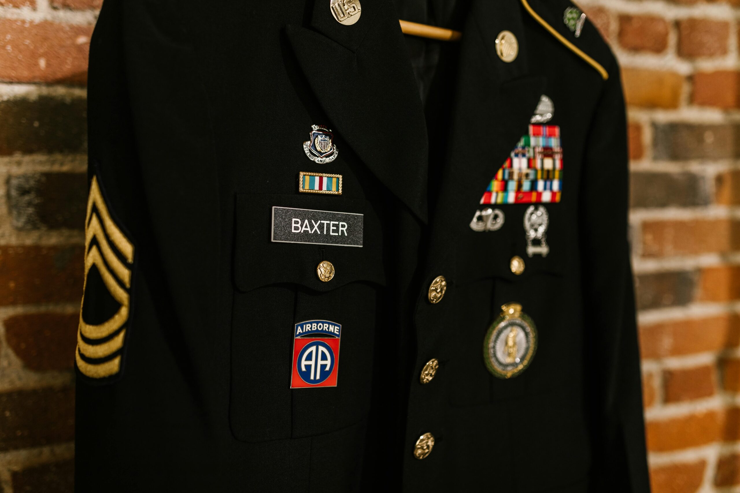 Close-up of a decorated military uniform with badges and medals against a brick wall background.